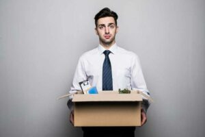 zwolniony pracownik trzyma karton ze swoimi rzeczami