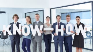 grupa pracowników trzymająca w dłoniach litery tworzące napis know-how